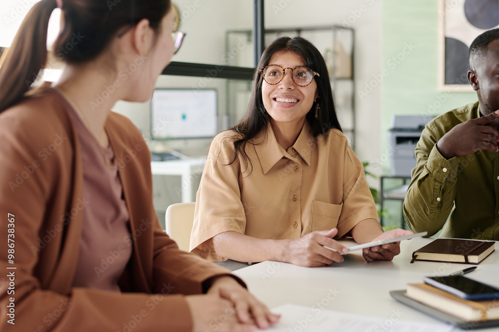 Aufkleber smiling woman wearing glasses engaging colleagues at meeting table in modern office with large windo
