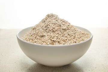Top view of whole wheat, oat flakes on white plate with white marble bottom