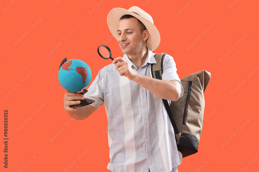 Wall mural male tourist with globe and magnifier on orange background