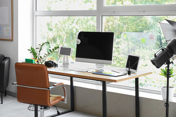 Photographer workplace with computer, laptop and photo camera in modern studio