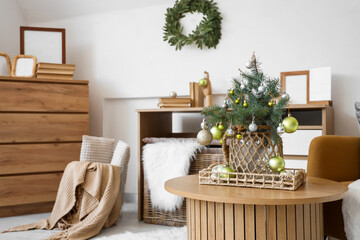 Small Christmas tree with baubles on coffee table in festive living room