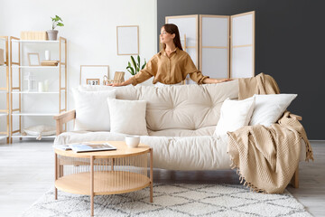 Pretty young woman near sofa  at home