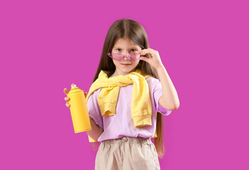 Little girl with spray paint can on purple background