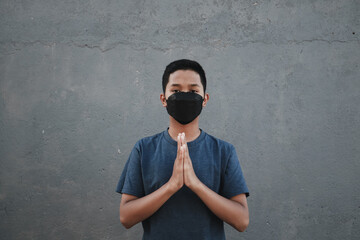 A teenager wearing a mask using both hands as a symbol of apology
