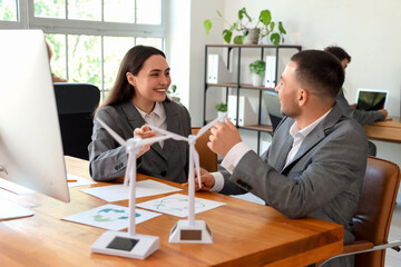 Young engineers working with wind turbine models on table in office