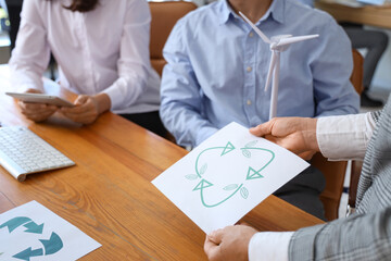 Engineers with recycle sign and wind turbine model in office, closeup