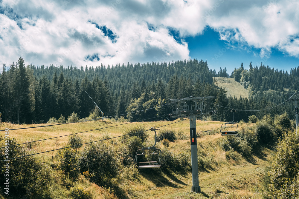 Wall mural a serene mountain landscape showcasing chairlifts amidst lush green hills and a bright, cloudy sky i