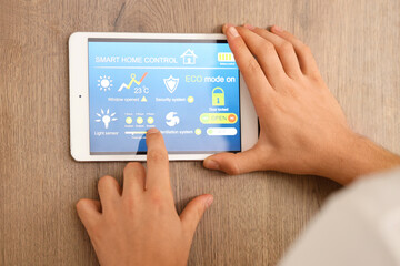 Young man using smart home control panel in kitchen, closeup