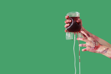Zombie hands with blood pack on green background. Halloween celebration