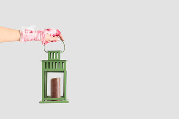 Mummy hand holding lantern with candle on grey background. Halloween celebration