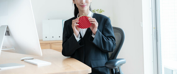 財布を持ち笑顔のスーツを着た女性