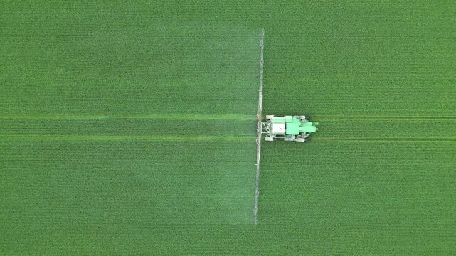 Vertical aerial view of an agricultural machine spreading a product on a field - Vue a&eacute;rienne verticale d'une machine agricole &eacute;pandant un produit phytosanitaire sur un champ