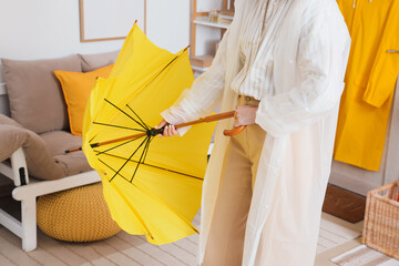 Woman with raincoat and umbrella in hallway