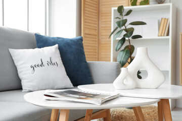 Coffee table with modern vases and magazines in living room, closeup