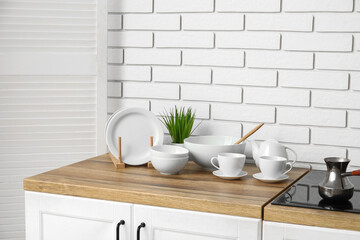 Porcelain teapot, cups, bowls and plates on wooden counter in kitchen