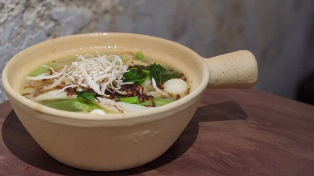 Close-up view of the claypot yee mee with vegetable, fish balls, shredded chicken and soup.