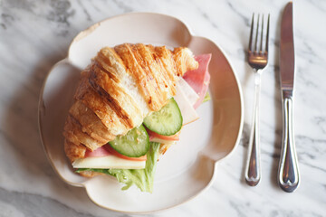 Indulge in a Delicious Croissant Sandwich filled with Fresh Vegetables and Savory Ham