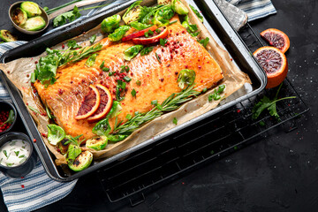 Cooked seafood on a black background. Baked salmon with onion, lemon, pomegranate juice