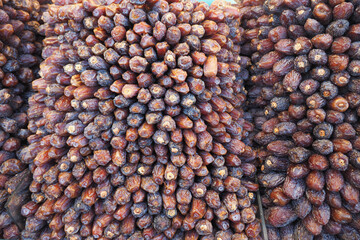Dried dates are piled high in a bustling market, attracting shoppers with their rich sweetness