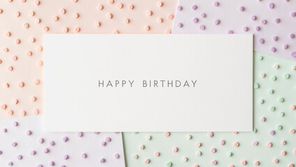 Fototapeta premium Happy birthday greeting card with Soft, delicate, pastel-hued polka dots in pale shades of peach, lavender, and mint green are scattered in seemingly random yet harmonious pattern across a white card