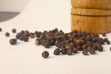 Black pepper and black pepper grinder on white background