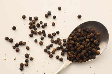 Black pepper on stainless steel spoon on white background