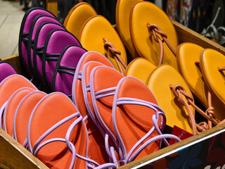 A colorful box filled with a variety of purple and orange flip flops