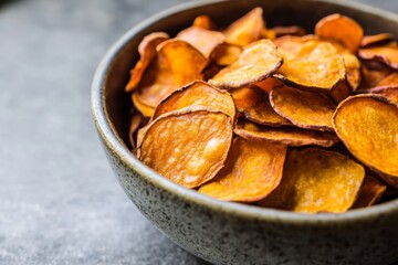 Fototapeta premium A bowl of homemade sweet potato chips, highlighting a healthy and crispy snack alternative to traditional potato chips. These delicious chips are rich in flavor and offer a nutritious option