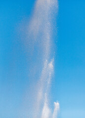 Water splashes from a fountain against a blue sky