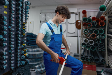 Salesman cutting pipe for client of plumbing hypermarket shop cropped shot