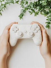 Hands holding wireless game controller on lush green plant background with copy space