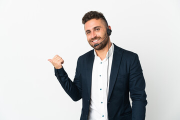 Telemarketer man working with a headset isolated on white background pointing to the side to present a product