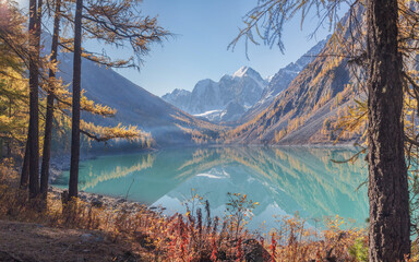 Mountain lake in the fall morning, scenic reflection, snow-capped peaks and mountain slopes