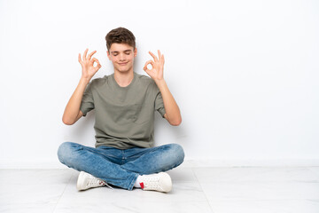 Teenager Russian man sitting on the floor isolated on white background in zen pose