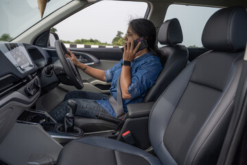 Pretty Indian woman using mobile phone in the car 