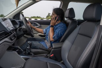 Pretty Indian woman using mobile phone in the car 