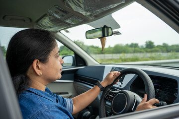 Naklejka premium Happy indian woman driving a car in the city. Portrait of smiling female with safety belt traveling in her auto.
