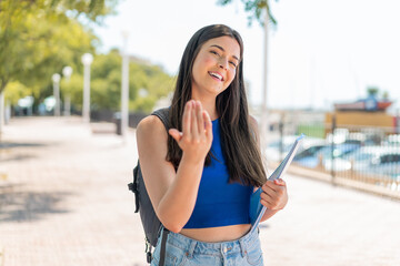 Young Brazilian student woman at outdoors inviting to come with hand. Happy that you came