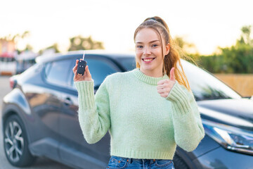 Young pretty girl holding car keys at outdoors pointing up a great idea