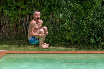 A man dives into the pool with a comical expression