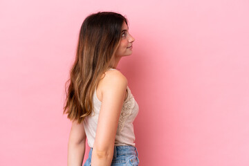 Young caucasian woman isolated on pink background in back position and looking back