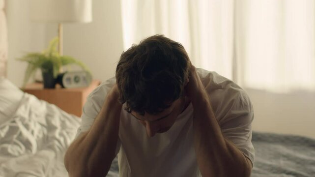 Caucasian man guy male bedroom despair hopeless situation problems difficulties crisis pain holding head grief anxiety distraught displeased frustration disappointment exhaustion distress overwhelmed