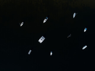 Top down dire of boats dotted in dark water of lake at midday