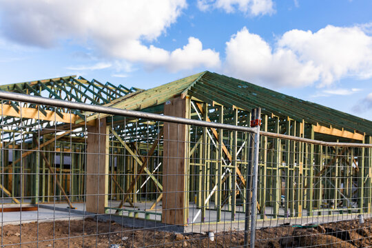 house being built with a timber frame behind temporary fencing