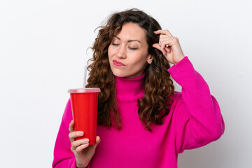 Fototapeta premium Young caucasian woman drinking soda isolated on white background having doubts and with confuse face expression