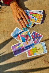 PALMA, SPAIN-August 29,2024;A hand with turquoise nails and a silver ring rests on scattered tarot...