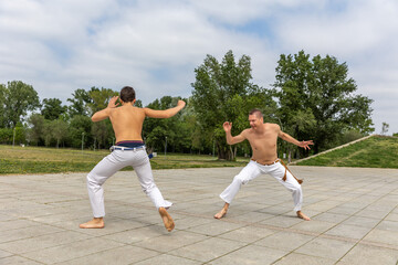Obraz premium Teenager and middle aged man practicing capoeira , brazilian martial art
