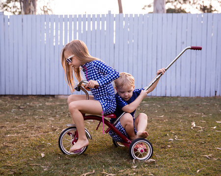 kids playing on a trike in their back yard