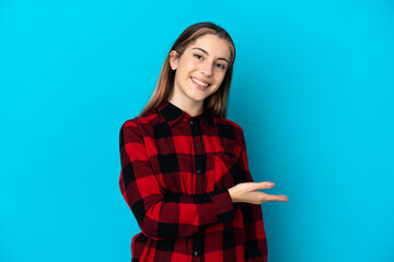 Young caucasian woman isolated on blue background presenting an idea while looking smiling towards