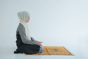 Muslim woman sitting on the floor, praying and asking for blessings to God. on white background. to person and faith in religion Islam concept.